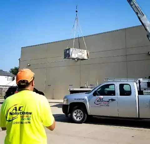 Using a crane, we position a brand new commercial HVAC unit on the rooftop of a commercial building.